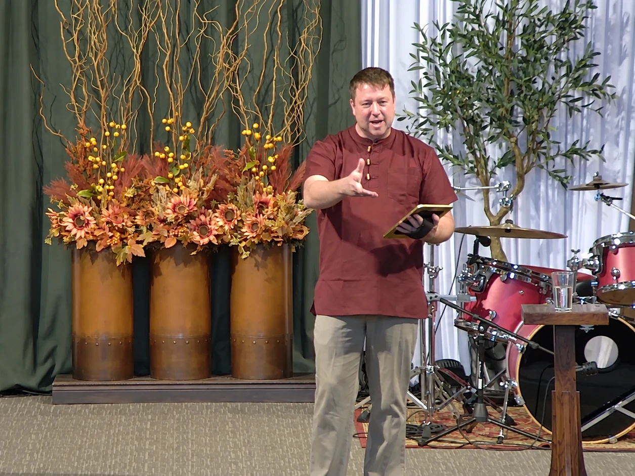 Pastor Clint Laird teaching at Calvary SonRise, holding a tablet and gesturing toward the congregation